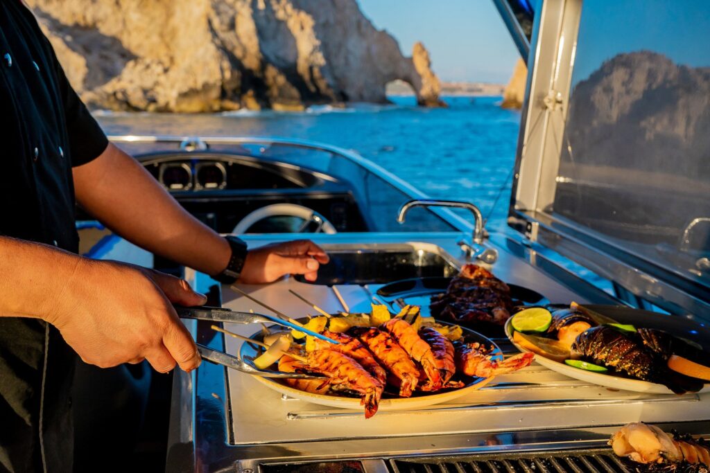 Private chef cooking for guests on the upper galley grilling shrimp on a bbq for our charter guests on our 80 foot Sunseeker Manhattan yacht in Cabo San Lucas, MX